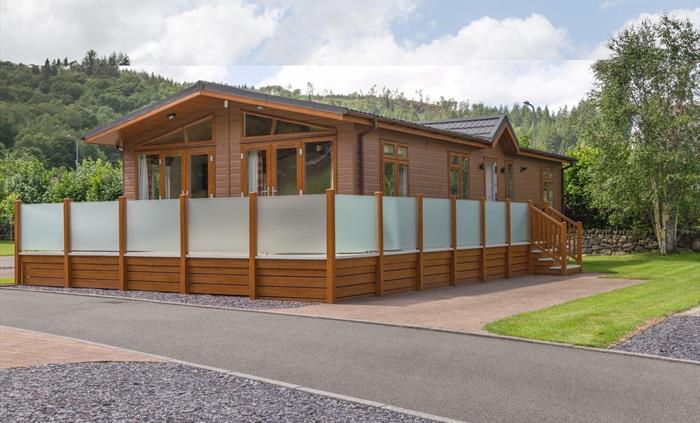 Large Luxurious Lodge with Private Parking by the accommodation, set within open grounds with a backdrop of open fields and forests.